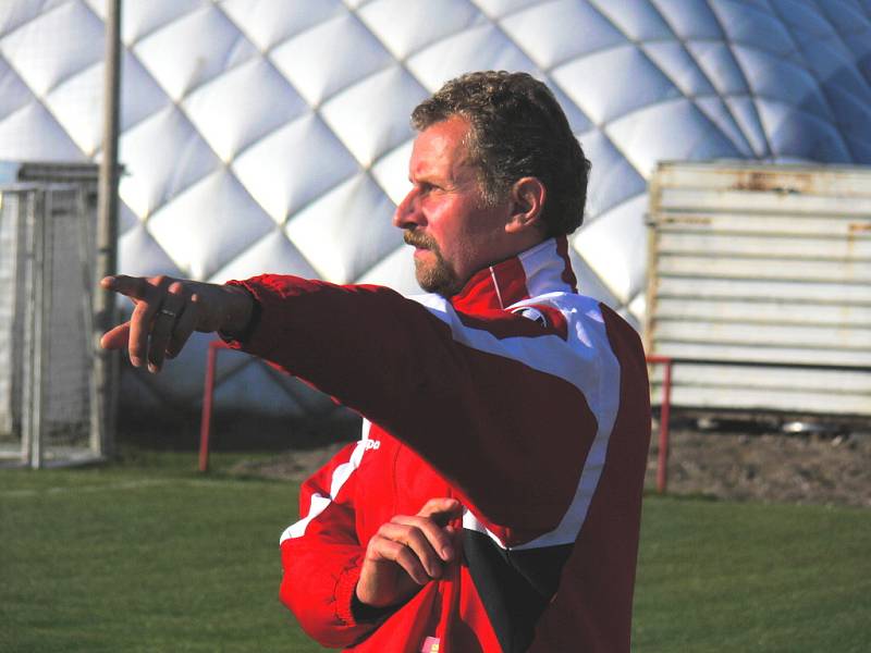 Trenér Karel Tondr ukazuje pokyny na hřišti, v pozadí nafukovací hala